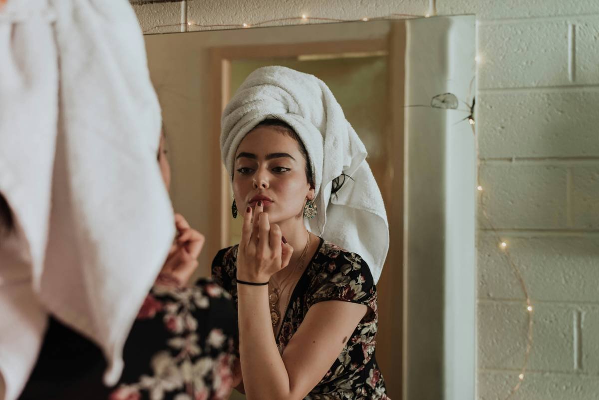 event makeup for evening featuring a model with smoky eyes, contoured cheekbones, and bold red lips under warm ambient lighting