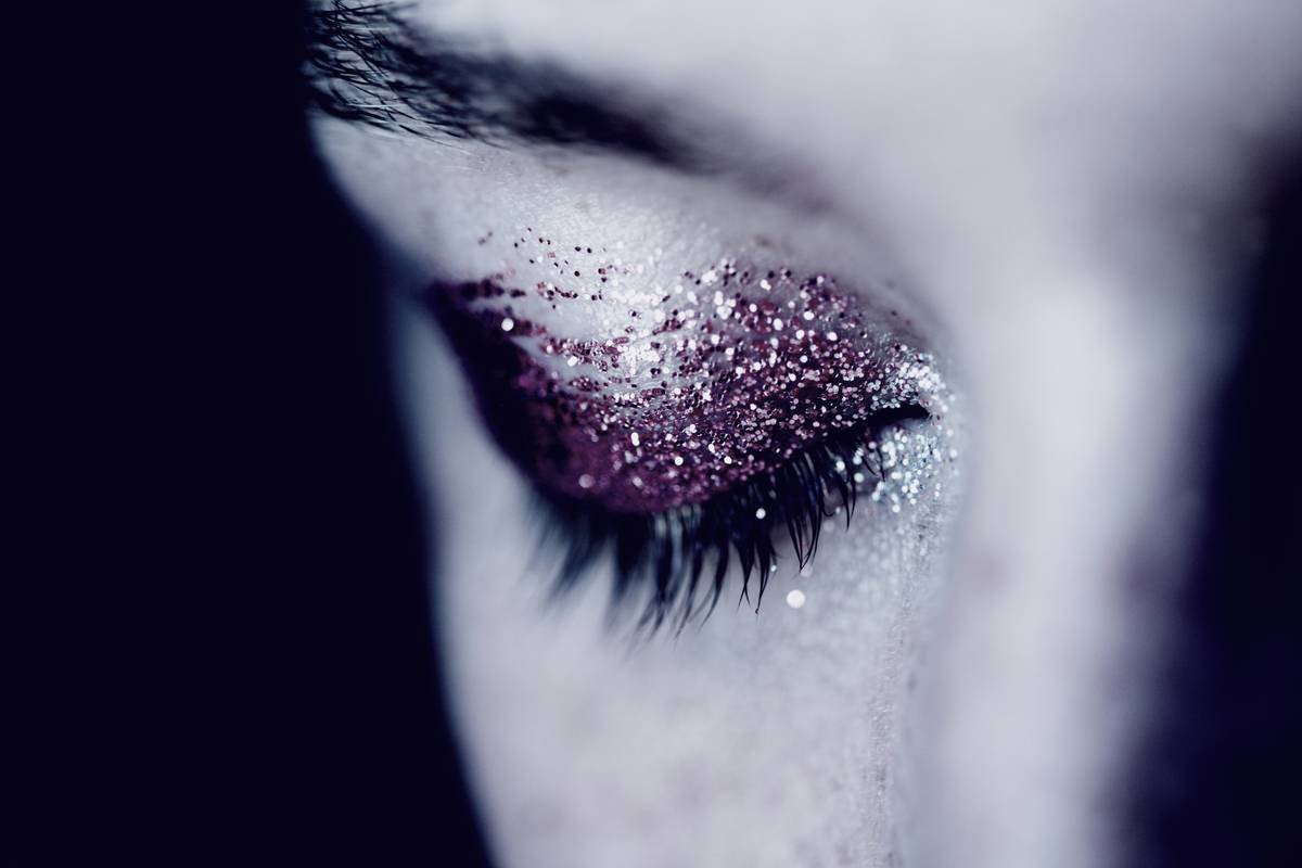 holiday party makeup with long-wear foundation, waterproof eyeliner, and subtle gold highlighter on model in festive red dress